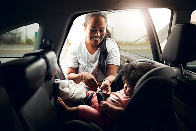Buy stock photo Shot of a woman strapping her baby into its car seat