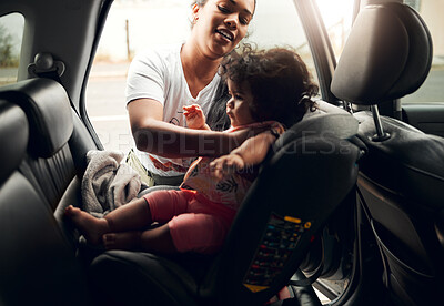 Buy stock photo Shot of a young woman strapping her baby into her car seat