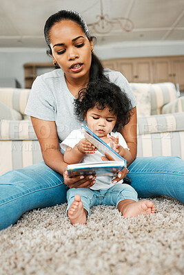 Buy stock photo Shot of a young mother reading to her baby girl
