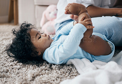 Buy stock photo Full length shot of an adorable little baby lying on her back and looking at her feet in the living room at home