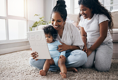 Buy stock photo Full length shot of a young woman sitting in the living room with her children and using a digital tablet