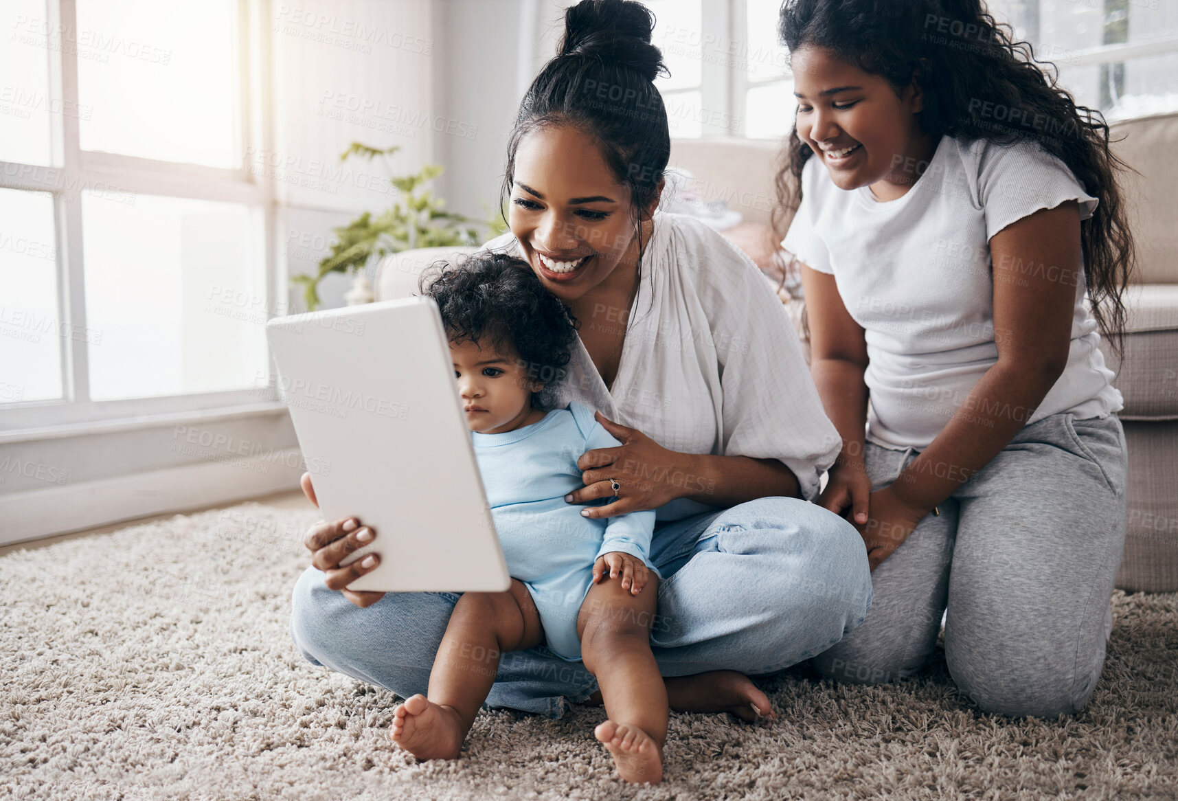 Buy stock photo Full length shot of a young woman sitting in the living room with her children and using a digital tablet