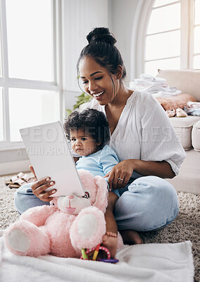 Buy stock photo Full length shot of a young woman sitting in the living room with her daughter and using a digital tablet