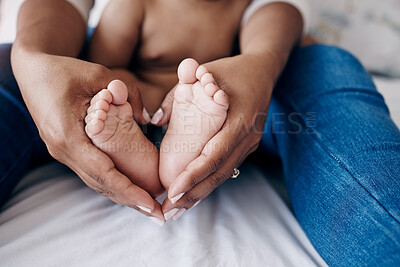 Buy stock photo Cropped shot of an unrecognisable woman sitting on the bed at home and holding her baby's feet