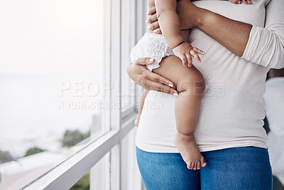 Buy stock photo Cropped shot of an unrecognisable woman standing at home and carrying her baby
