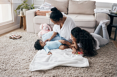 Buy stock photo Full length shot of an attractive young woman sitting on the living room floor and bonding with her children