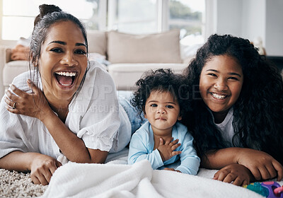 Buy stock photo Shot of an attractive young woman lying on the living room floor and bonding with her children