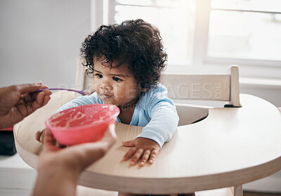 Buy stock photo Shot of an adorable little girl sitting in the kitchen and being fed by her mother