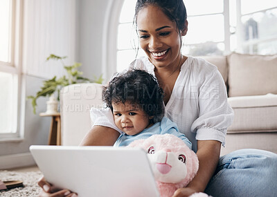 Buy stock photo Shot of an attractive young woman sitting on the living room floor with her daughter and using a digital tablet