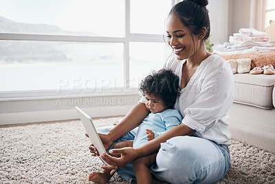 Buy stock photo Shot of an attractive young woman sitting on the living room floor with her daughter and using a digital tablet