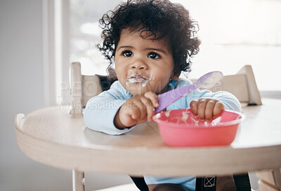Buy stock photo Shot of an adorable little girl sitting alone in the kitchen and eating her breakfast