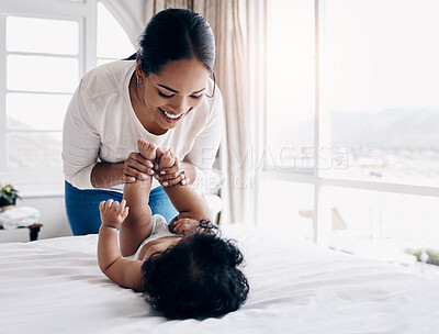 Buy stock photo Shot of an attractive young woman bonding with her baby at home while changing her diaper