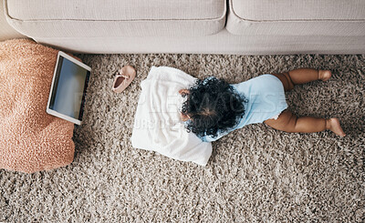 Buy stock photo High angle shot of an unrecognisable baby lying on the living room floor and watching a video on a digital tablet