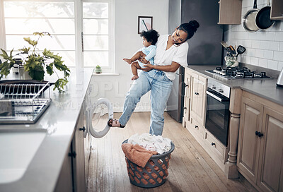 Buy stock photo Shot of a young mother using a cellphone while completing housework and holding her baby at home