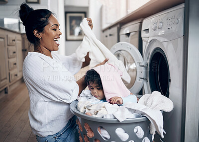 Buy stock photo Shot of a young mother playfully bonding with her baby girl while doing the laundry at home
