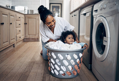 Buy stock photo Mom, baby and playing with laundry basket in home, helping and multitasking with chores. Mother, support daughter and housekeeping with child in kitchen, cleaning and clothes for washing machine