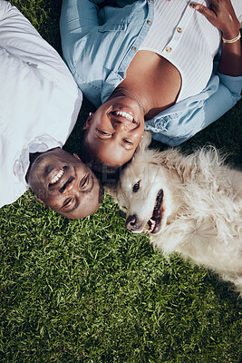 Buy stock photo Shot of a young couple lying on the grass with their dog in their garden at home