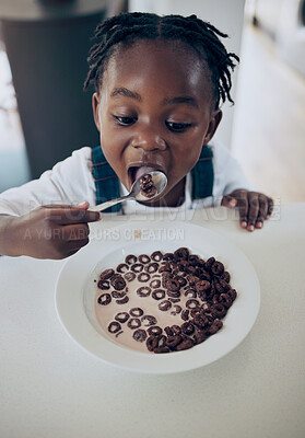 Buy stock photo Shot of an adorable little girl sitting alone in the kitchen and eating his breakfast