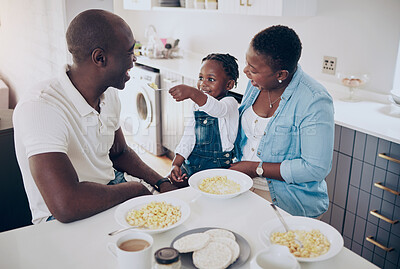 Buy stock photo Shot of a happy young family bonding while eating breakfast in the kitchen at home