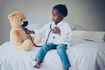 Buy stock photo Shot of a little girl pretending to be a doctor while examining her teddybear at home