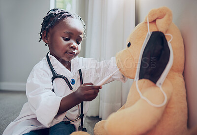 Buy stock photo Shot of a little girl pretending to be a doctor while examining her teddybear at home