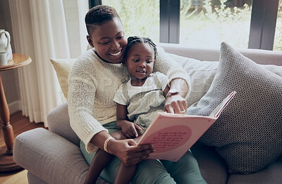 Buy stock photo Shot of a mother reading a book with her daughter at home