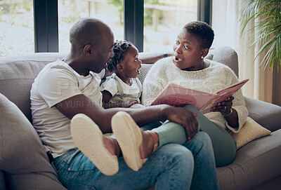Buy stock photo Shot of a young family reading a book together at home