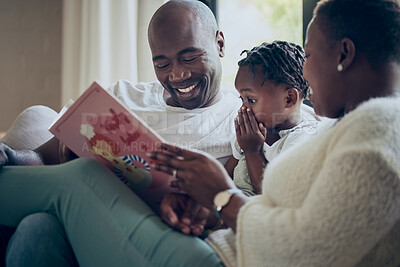 Buy stock photo Shot of a young family reading a book together at home