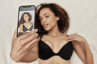 Buy stock photo Shot of a woman taking a selfie while lying in lingerie