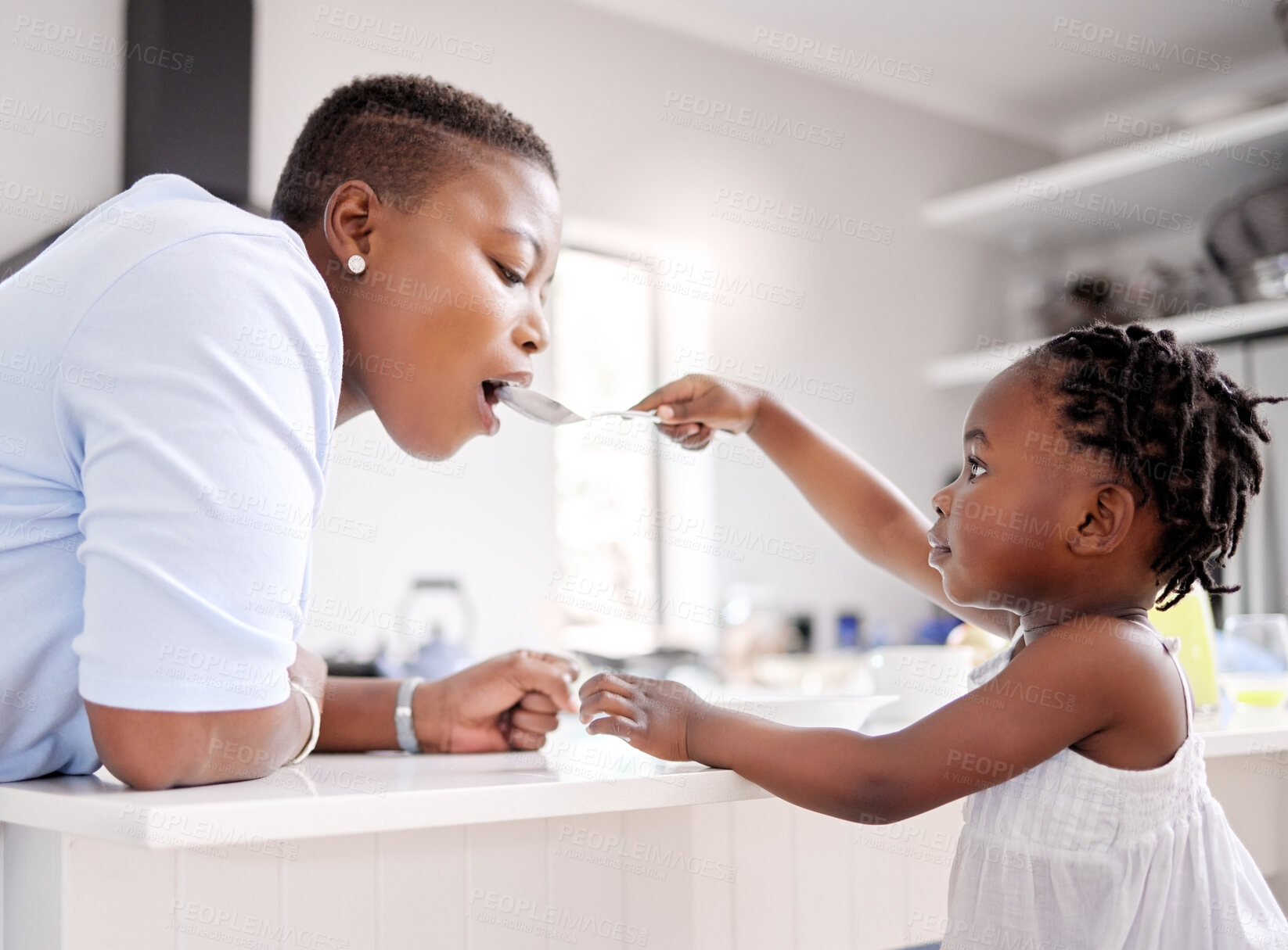 Buy stock photo Black child, feeding and mother with spoon in kitchen for food, meal or share together at home. Young African, little girl or kid giving mom a taste of cereal bowl for breakfast, fiber or calcium