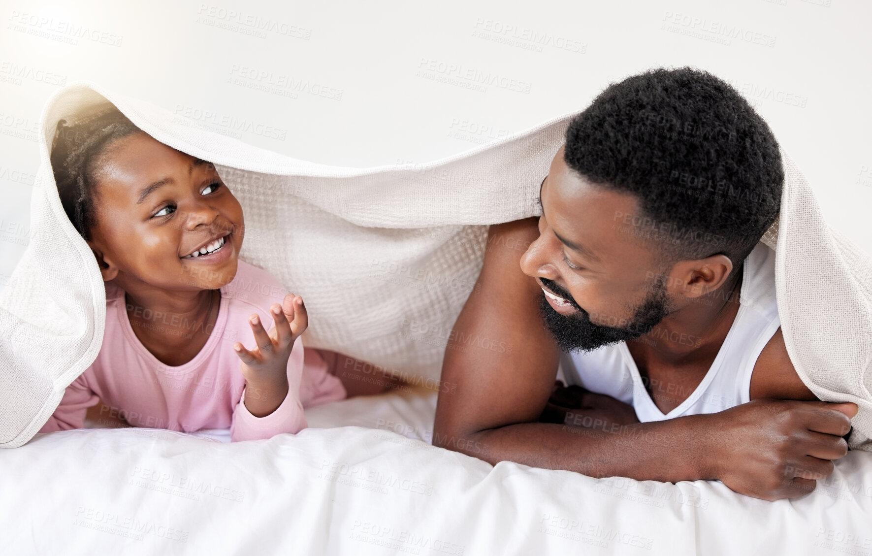 Buy stock photo Shot of a handsome young man bonding with his daughter in bed at home