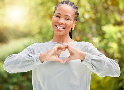 Buy stock photo Shot of a young woman making a heart gesture with her hands in nature