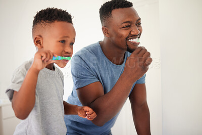 Buy stock photo Father brushing his teeth with his child for oral hygiene, health and wellness in the bathroom. Dental, teaching and young African man doing his morning mouth routine with his boy kid at their home.