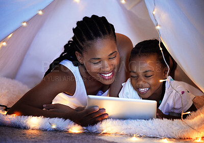 Buy stock photo Shot of a mother and her daughter using a digital tablet together while relaxing under a blanket fort at home