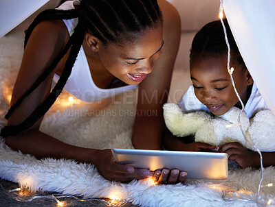 Buy stock photo Shot of a mother and her daughter using a digital tablet together while relaxing under a blanket fort at home