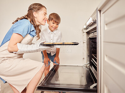 Buy stock photo Shot of a mother and son inserting a tray of cookies into the oven