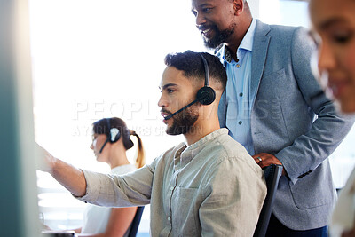 Buy stock photo Shot of a handsome young call centre agent sitting and using his computer while his manager watches