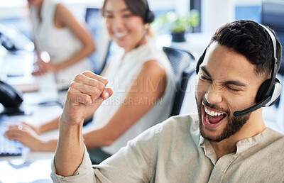 Buy stock photo Shot of a handsome young call centre agent sitting in the office and celebrating a success