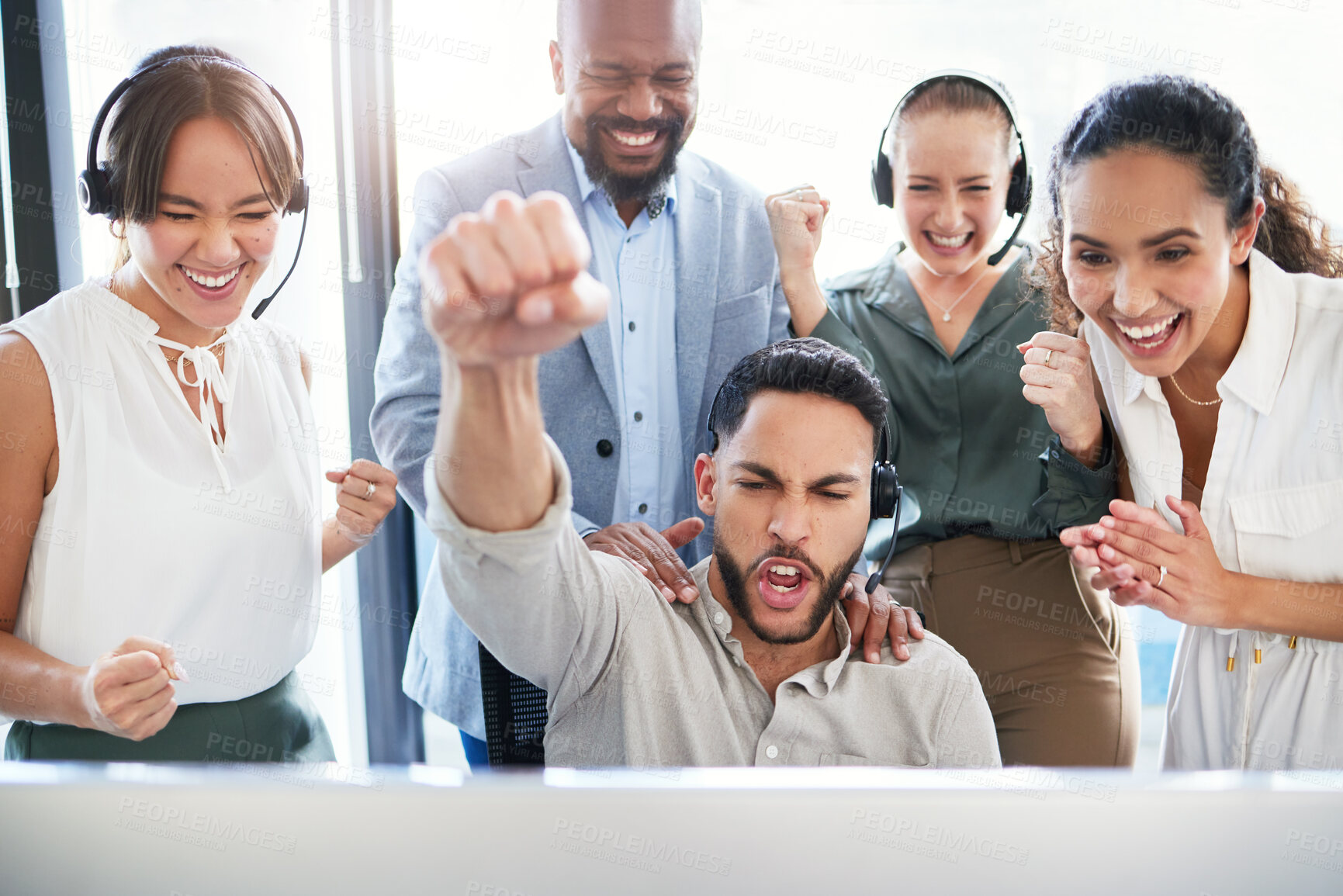 Buy stock photo Shot of a handsome young call centre agent sitting and celebrating a success while his team support him