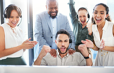 Buy stock photo Shot of a handsome young call centre agent sitting and celebrating a success while his team support him
