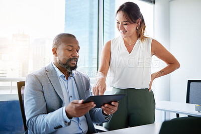 Buy stock photo Shot of two businesspeople having a discussion in the office while using a digital tablet