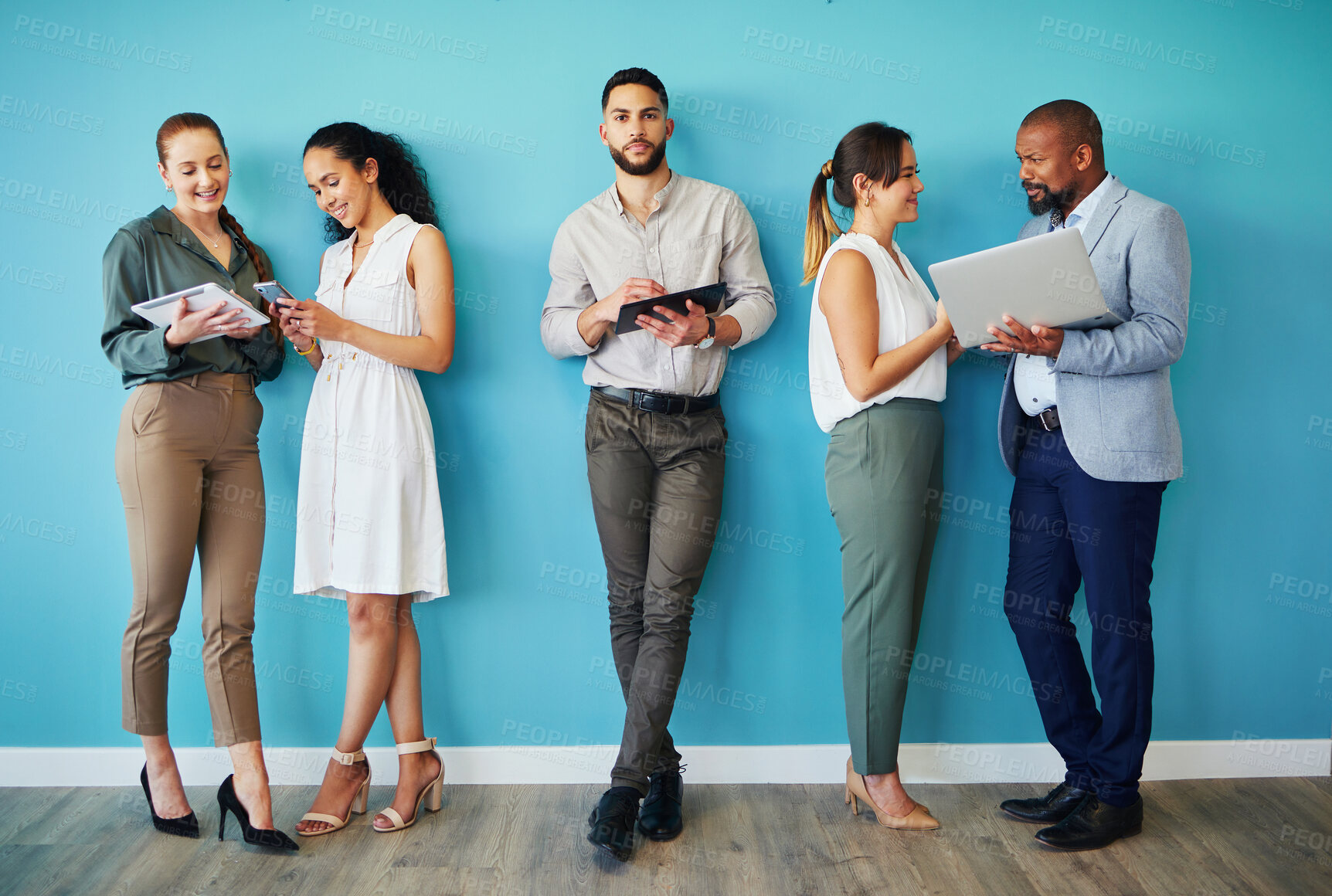 Buy stock photo Full length shot of a diverse group of businesspeople standing together in the office and using technology