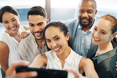 Buy stock photo Shot of a diverse group of businesspeople standing together in the office and taking selfies on a cellphone
