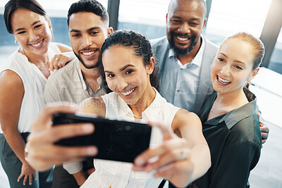 Buy stock photo Shot of a diverse group of businesspeople standing together in the office and taking selfies on a cellphone