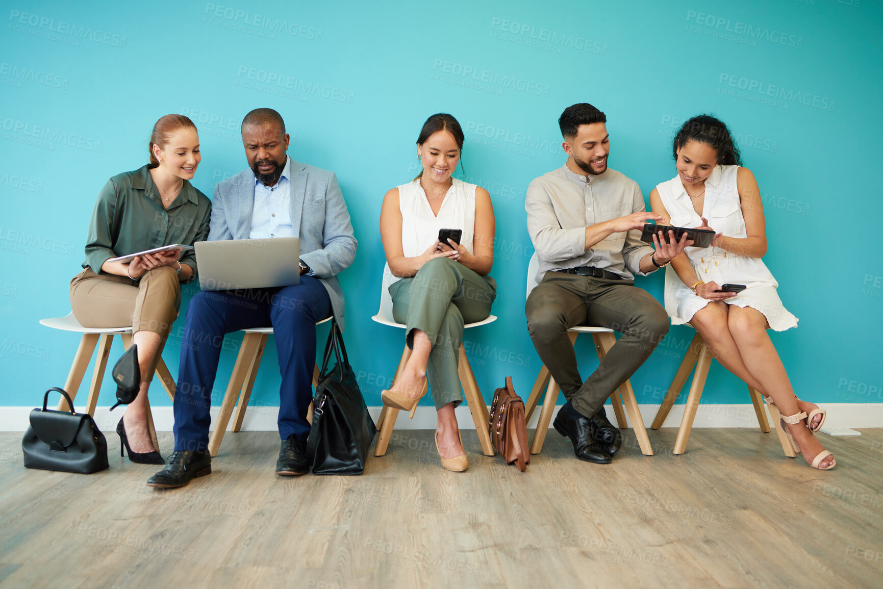 Buy stock photo Full length shot of a diverse group of businesspeople sitting together in the office and using technology