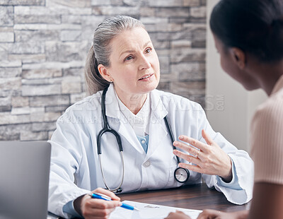 Buy stock photo Shot of a doctor going through paperwork during a consultation with a patient in a medical office