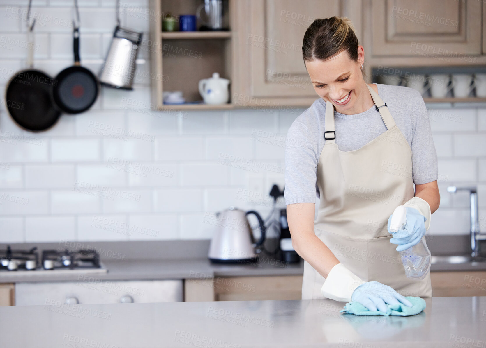 Buy stock photo Cleaning, wipe and woman with smile kitchen counter with cloth for hygiene, remove bacteria or chores. Apron, sanitizer and person with spray bottle for housekeeping, detergent or disinfect in home