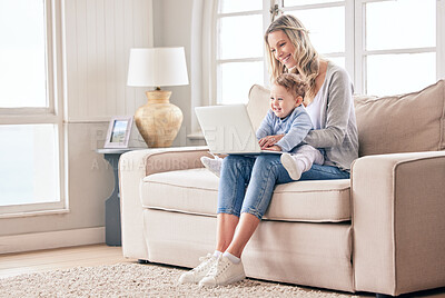 Buy stock photo Shot of a woman working on her laptop while keeping her baby on her lap