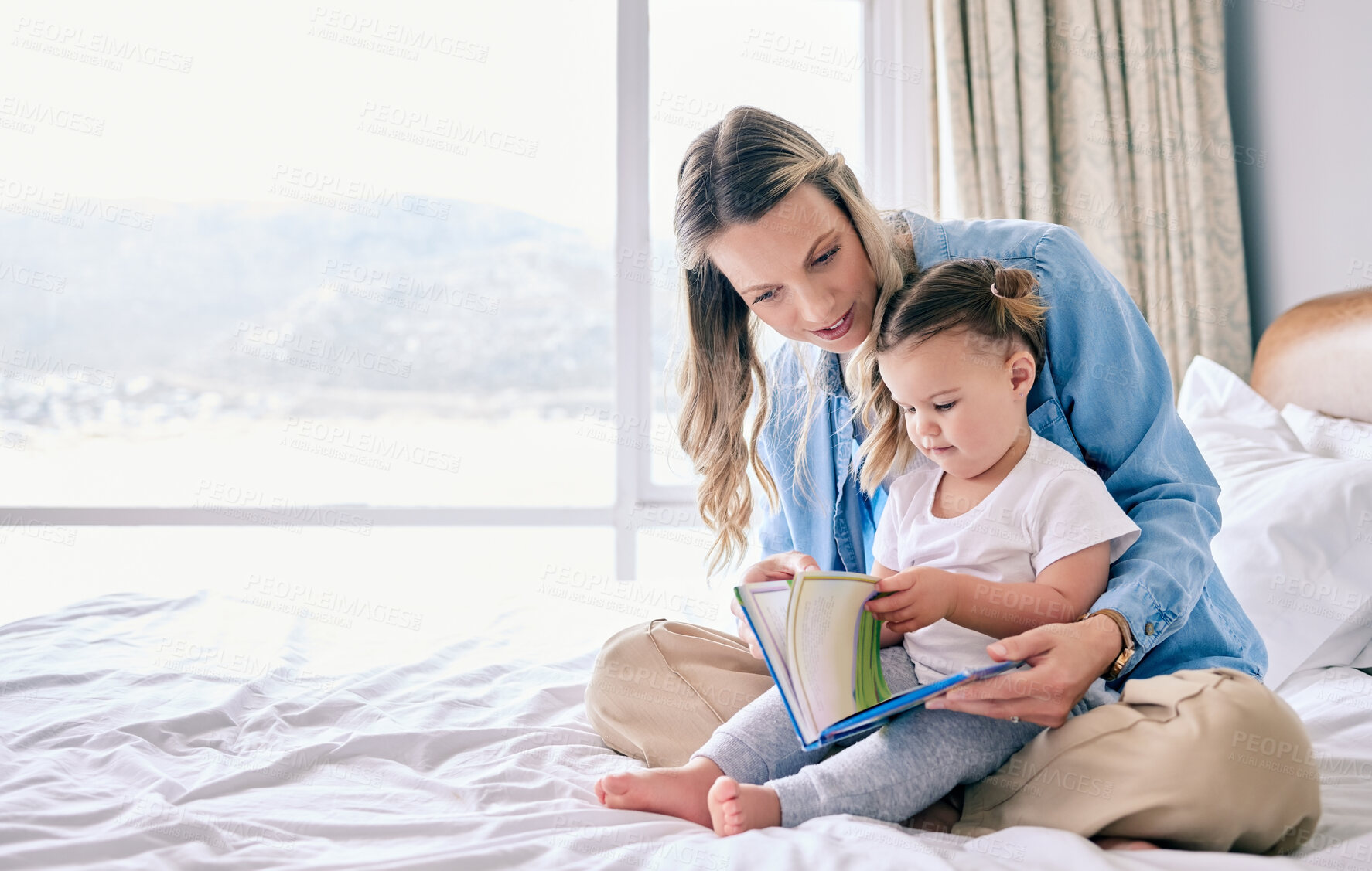 Buy stock photo Shot of a woman reading to her adorable daughter at home