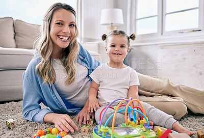 Buy stock photo Shot of a mom sitting with her daughter while she plays with her toys